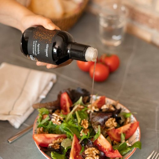 Prisvindende Muscat- og appelsinhonningeddike fra Alemany, hældes på en salat.