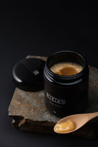 sjælden og exceptionel Hikiän – finsk honning i sin reneste form, i ekslusiv sort glas, på et bord. 