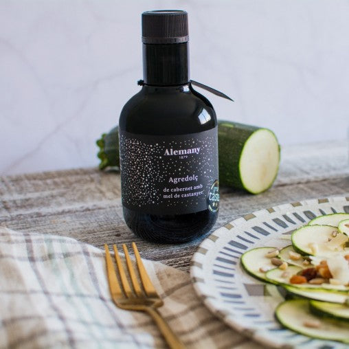 Flaske med prisvindende Alemany vineddike med kastanjehonning – sød-sur Cabernet Sauvignon fra Alemany på bord med en salat.