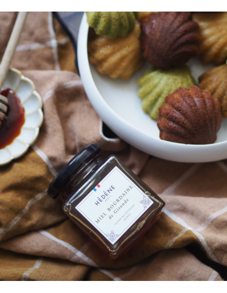 Glas med Hédéne  Havtorn honning,  Bourdaine de Gironde,  på et bord med dug og fad med kager,  Frankrig