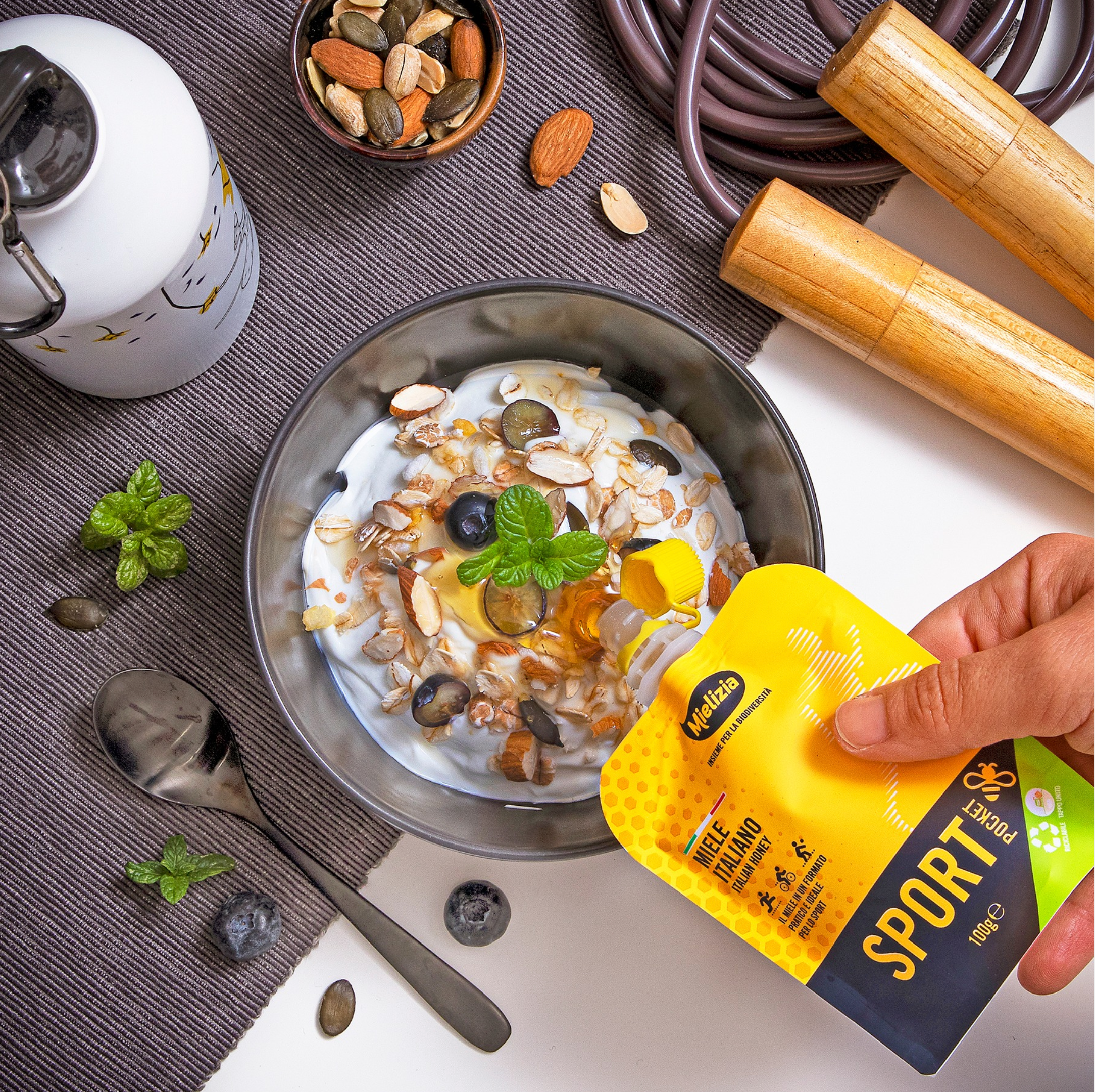 Morganmads bord med en skål med yougurt og mûslie samt en sports sachet fra Miliezia der hældes over